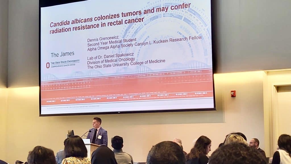 White male medical student presenting research at a conference